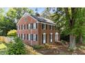 Charming brick two-story home showcasing a landscaped yard with mature trees at 925 S Chestnut St, Henderson, NC 27536