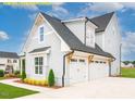 Side view of a home with a two-car garage and charming architectural details, complemented by landscaping at 1036 Smoke Willow Way, Rolesville, NC 27571