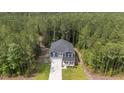A high-angle view displays a charming two-story home nestled within a dense forest setting at 120 Rocking Horse Ln, Sanford, NC 27332