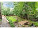 Lush backyard garden featuring a small bridge over stream and manicured landscaping at 12212 Ashton Woods Ln, Raleigh, NC 27614