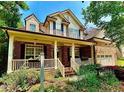Inviting two-story brick home with a covered front porch, complemented by lush greenery and a well-manicured lawn at 12212 Ashton Woods Ln, Raleigh, NC 27614