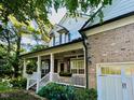 Lovely brick home with a cozy front porch framed by white columns and surrounded by mature trees at 12212 Ashton Woods Ln, Raleigh, NC 27614