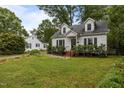 Quaint white home with black shutters, brick steps, and a well-maintained lawn at 1541 Shadylawn Dr, Burlington, NC 27215