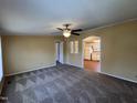 Spacious living room with neutral carpet, ceiling fan, and archway leading to the bright, white kitchen at 195 Washington Ln, Cameron, NC 28326
