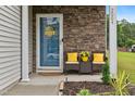 Inviting front porch with a blue door, chairs with yellow cushions, and decorative plants at 2004 Tennessee Rd, Durham, NC 27704