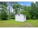 A well-maintained, white outbuilding sits in a sunny, verdant yard, perfect for storage at 202 Hamilton Rd, Bunnlevel, NC 28323