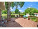 Large wooden deck with seating overlooking a beautiful backyard featuring a pool, fire pit, and green space at 2925 Redwood Rd, Durham, NC 27704