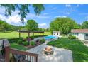 Lush backyard featuring a pergola with seating, a fire pit, an in-ground pool, and a pool house at 2925 Redwood Rd, Durham, NC 27704