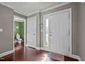 Bright foyer featuring wood flooring, white trim, and a door to the bathroom and doorway to other rooms at 5321 Longspur Dr, Snow Camp, NC 27349