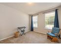 Cozy bedroom with two windows dressed with blue curtains, neutral carpeting, and a comfortable rocking chair at 6512 Blalock Forest Dr, Willow Springs, NC 27592