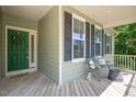Inviting front porch with wooden floors, a green front door, and seating area, perfect for enjoying outdoor moments at 6512 Blalock Forest Dr, Willow Springs, NC 27592