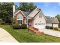 Charming home featuring a two-car garage and brick accents, complemented by lush greenery at 6728 Pointe Vista Cir, Raleigh, NC 27615