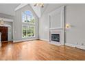 Spacious living room with hardwood floors, fireplace, and large windows overlooking the backyard at 6728 Pointe Vista Cir, Raleigh, NC 27615