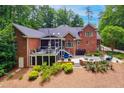 Back of a brick home with a spacious deck, screened porch, and outdoor seating area at 8 Pine Top Pl, Durham, NC 27705