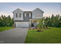 Two-story home boasts a well-manicured lawn, two-car garage, and modern gray siding at 89 Merle Way, Wendell, NC 27591