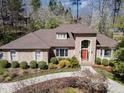 Aerial view of a brick home with an arched entryway, lovely landscaping, and a long driveway at 10210 Governors Drive Dr, Chapel Hill, NC 27517