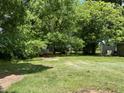 Expansive backyard view featuring mature trees, green grass, and an outbuilding at the rear of the property at 1202 Kilby St, Burlington, NC 27215