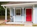 Inviting front porch with a rocking chair, bright red door, and white trim details at 2 Capri Ter, Durham, NC 27703