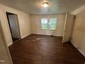 Bedroom with wood floors, cream-colored walls, two doors, one window, and a view of the outside at 2302 Chautauqua Ave, Durham, NC 27707