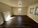 Spacious living room with dark wood floors, cream walls, white fireplace mantle and natural light from two windows at 2302 Chautauqua Ave, Durham, NC 27707