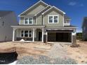 Two-story home under construction featuring board and batten siding, a brick facade, and a welcoming covered front porch at 245 Tidal Pool Way, Cary, NC 27519