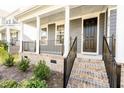 Inviting front porch with classic columns, brick accents, and black metal railings at 2918 Heirloom Way, Apex, NC 27502