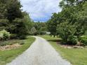 Long gravel driveway leading to a home surrounded by lush greenery and mature trees at 3110 Fieldstone Ln, Mebane, NC 27302
