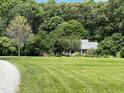 Spacious green lawn with a view of the brick home nestled among mature trees at 3110 Fieldstone Ln, Mebane, NC 27302