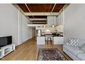 Open-concept living space featuring a modern kitchen, hardwood floors, and exposed beam ceiling at 500 N Duke St # 55-105, Durham, NC 27701