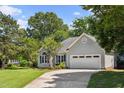 Beautiful one-story home with a manicured lawn, lush landscaping, and an attached two car garage at 6 Danesfield Ct, Durham, NC 27707