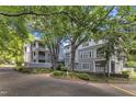 Attractive gray condos nestled among mature shade trees feature brick driveways and manicured landscaping at 700 Bishops Park Dr # 302, Raleigh, NC 27605