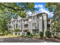 Beautiful condos with gray siding, bright white trim, patios, and balconies, surrounded by mature trees at 700 Bishops Park Dr # 302, Raleigh, NC 27605
