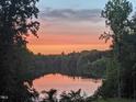 Picturesque lake view with a colorful sunset and lush trees reflected on the water at 7483 Danford Rd, Burlington, NC 27215
