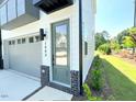 Contemporary townhome exterior showcasing a one-car garage, green door and brick accents at 1000 Regalia Rd # 1, Durham, NC 27713
