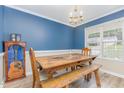 Dining room featuring blue accent wall, chandelier, farmhouse table with bench, and large window at 110 Oak Park Dr, Benson, NC 27504