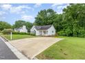 Inviting single-story home with white exterior, dark roof, ample driveway, and beautiful green lawn at 110 Oak Park Dr, Benson, NC 27504