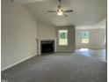 Bright living room with a corner fireplace, a ceiling fan, and views of the front yard at 111 Mahogany Way, Four Oaks, NC 27524