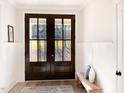Welcoming entryway with decorative double doors, light hardwood floors, wainscotting, and a bench at 1218 Rogers Farm Rd, Wake Forest, NC 27587