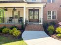 Inviting front porch with rocking chairs, hanging flower baskets, brick stairs, and double doors at 1218 Rogers Farm Rd, Wake Forest, NC 27587