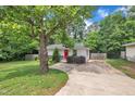 Charming single-story home featuring mature trees, vibrant landscaping, and a bright red front door at 1717 Martin Luther King Jr Blvd, Raleigh, NC 27610