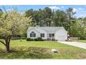 Quaint white home with an attached garage, green lawn, and trees surrounding the property at 1752 Cobblestone Dr, Creedmoor, NC 27522