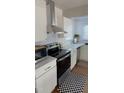 Bright kitchen with stainless steel appliances, white cabinets, and stylish black and white checkered rug at 200 S Pettigrew St, Raleigh, NC 27610