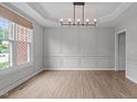 Light-filled dining room with detailed trim, hardwood floors, modern chandelier, and large windows at 2003 Red Sage Ct, Apex, NC 27502