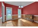 Elegant dining room featuring hardwood floors, red accent walls, and natural light from the windows at 203 N Becket St, Cary, NC 27513