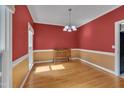Charming dining area with hardwood floors, paneled walls and bright red accent wall at 203 N Becket St, Cary, NC 27513