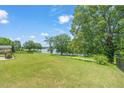 Expansive backyard featuring lush green grass and mature trees with lake views at 2404 Azalea Dr, Durham, NC 27703