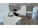 Open kitchen boasts stainless steel appliances, grey cabinets, and an island with a sink at 2411 Whitewing Ln, Wendell, NC 27591