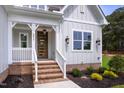 Inviting front porch with a modern, multi-paned door, brick steps and crisp white railing at 2617 Packhouse Rd, Zebulon, NC 27597