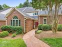 Charming brick home featuring a landscaped front yard and a welcoming brick pathway to the red front door at 3347 Ridgecrest Ct, Raleigh, NC 27607