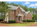 Two-story brick home featuring lush landscaping, a front entrance, and mature trees at 4412 Thistlehill Ct, Raleigh, NC 27616